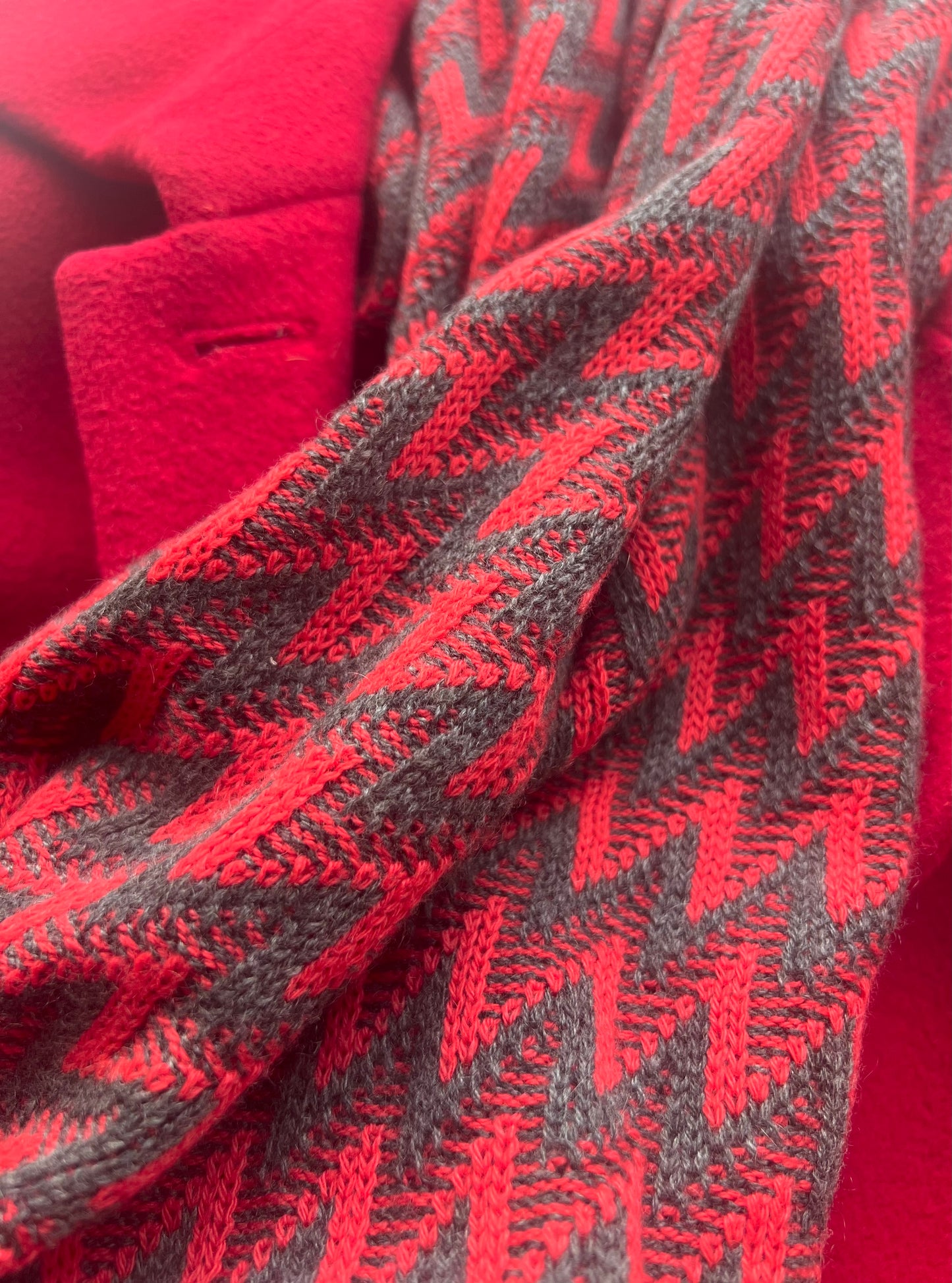 close up detail of the red and grey cashmere wrap as a scarf worn with a red coat