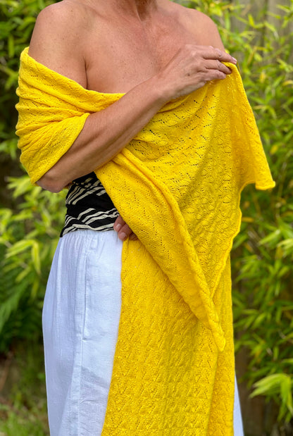 A bright yellow cashmere lace knit wrap wrapped around a woman to show length and width of this intricate cashmere lace 
