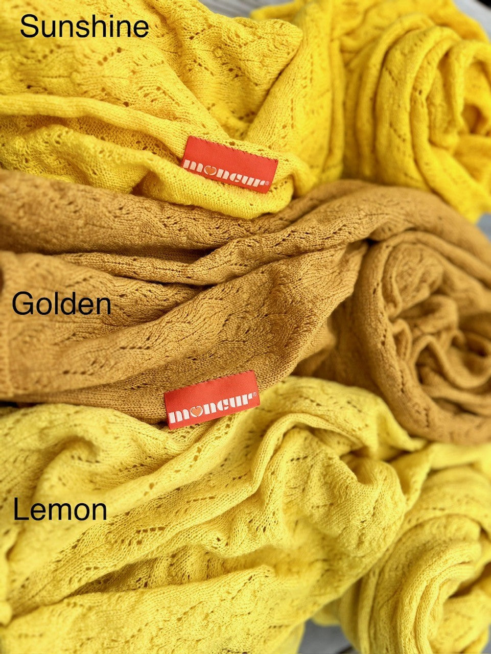 close up image of the colourways available in bright yellow shades of lace wrap with the soft satin moncur label hand stitched on 