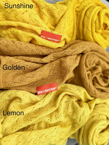 close up image of the colourways available in bright yellow shades of lace wrap with the soft satin moncur label hand stitched on 