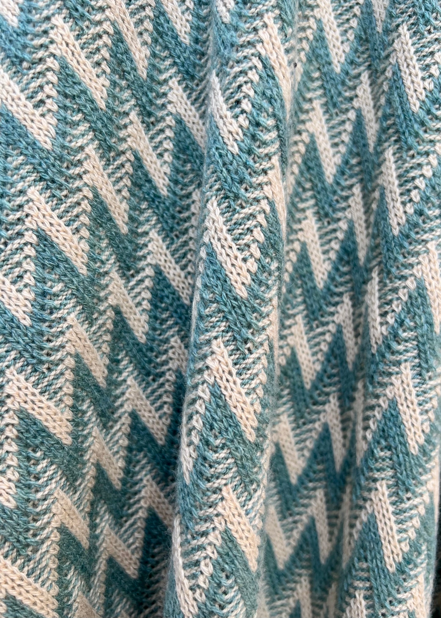 close up detail of the green and beige natural colours in the zig zag wrap in cashmere
