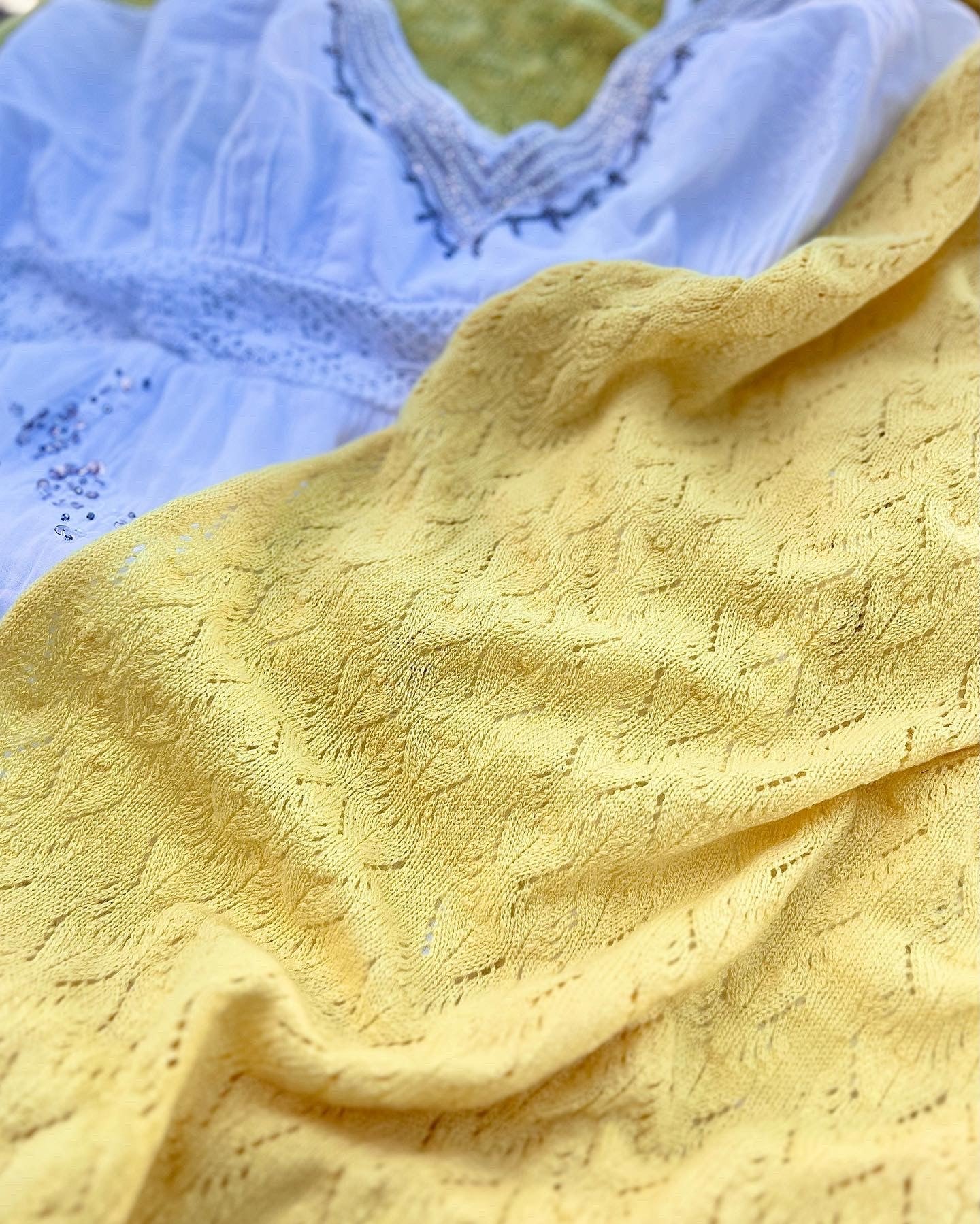 lemon Lacey cashmere shawl wrap made in scotland by moncur knitwear laid flat against a white broderie anglaise beaded dress 