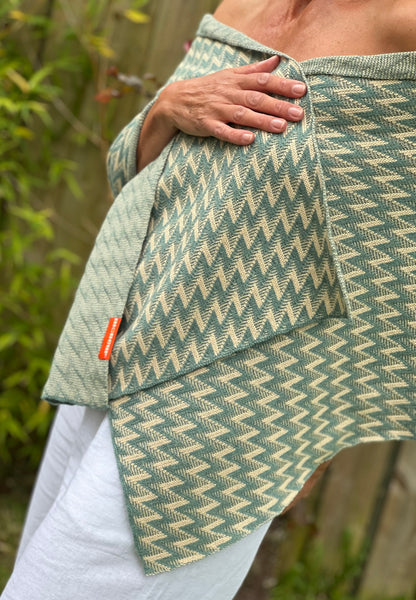 a person wearing a wide and luxuriously soft green zigzag patterned cashmere wrap 