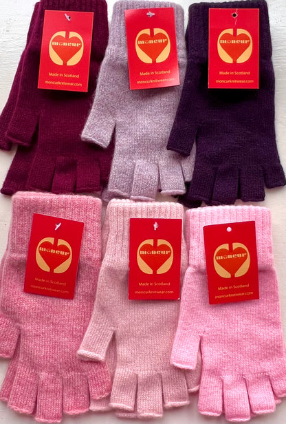 A collection of fingerless gloves in various shades of pink and purple, displayed with tags indicating the brand Moncur Knitwear.