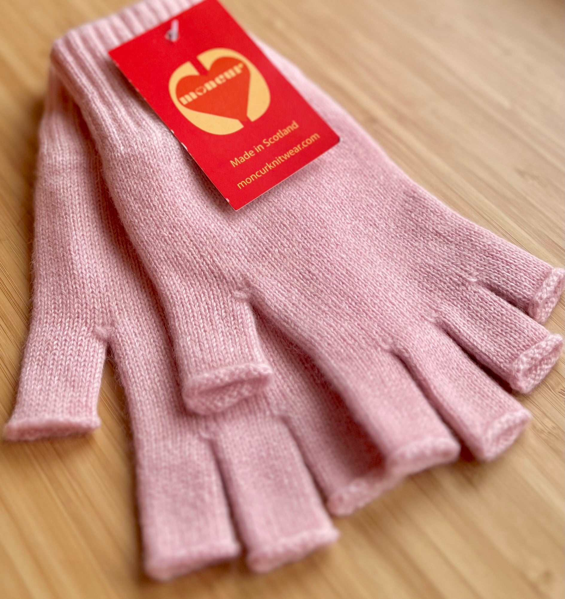 powder pink cashmere fingerless gloves displayed with tags indicating the brand Moncur Knitwear.
